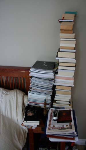 A photograph of a nightstand with stacked books